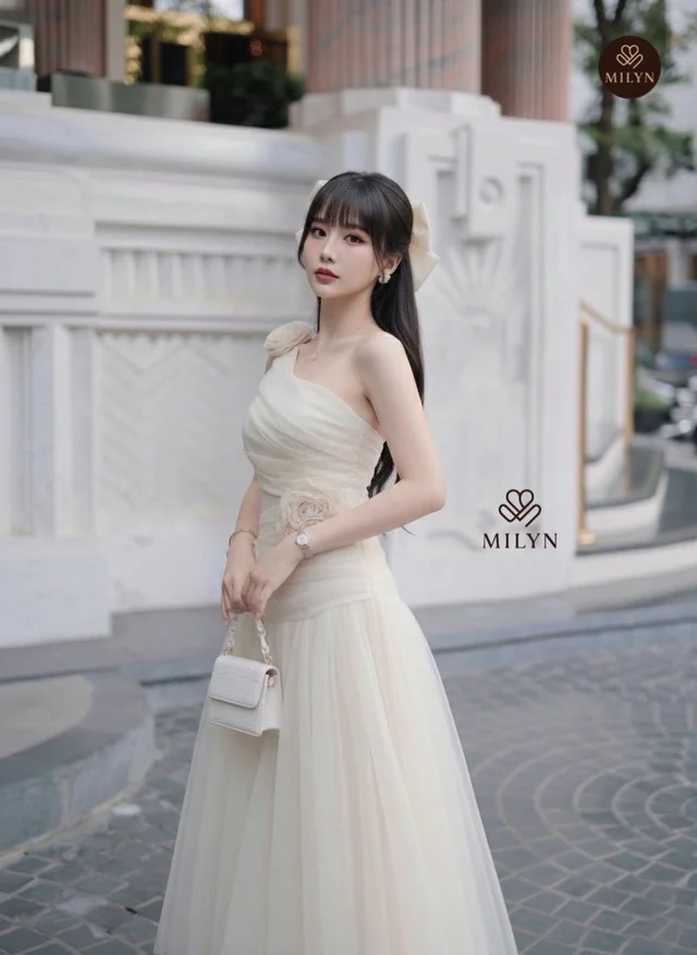 MILY เดรสยาวสีขาวครีมไหล่เดียวแต่งดอกไม้ลุคหวานหรู (alternate)